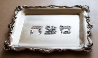 A silver tray with the word matzah written on it in Hebrew, designed for matzah, which is a special bread for Passover