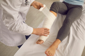 Cropped image doctor bandages the patient's broken leg with a bandage in the hospital. Doctor who...