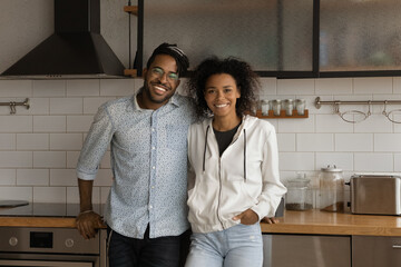 Portrait of happy cheerful young african family looking at camera embrace at stylish home kitchen....