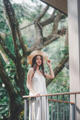 A beautiful woman in a white dress, wearing a straw hat, lounging in nature.