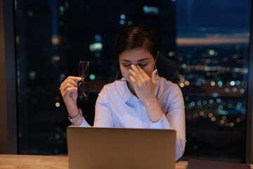 Exhausted young hindu lady take off glasses rub nose feel pain in dry eyes irritated by work before...