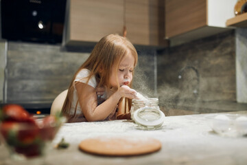 Happy little chef, flour, knead the dough. The cook girl blows on the flour. Home cooking. kitchen