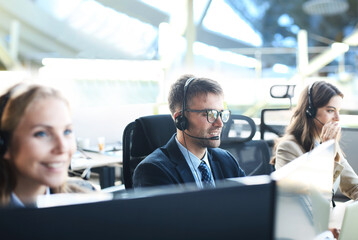 Portrait of call center worker accompanied by his team. Smiling customer support operator at work.