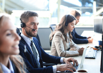 Portrait of call center worker accompanied by his team. Smiling customer support operator at work.