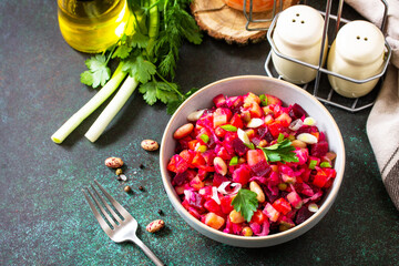 Beetroot salad vinaigrette with pickled cucumber, beans, carrots, peas, sauerkraut on a dark countertop. Copy space.