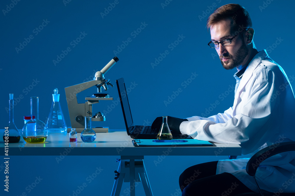 Poster laboratory testing. workplace chemist. man uses a laptop in lab. chemist conducts laboratory testing