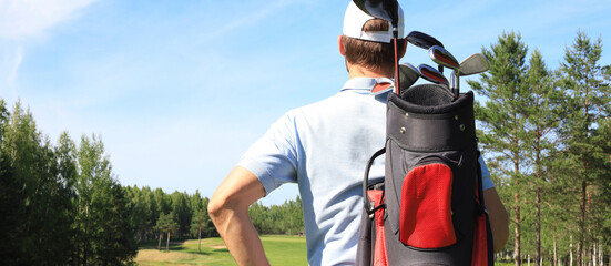 Golf player walking and carrying bag on course during summer game golfing.