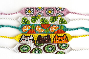 Woven DIY friendship bracelets handmade of embroidery bright thread with knots isolated on white...