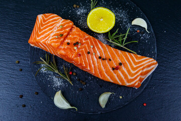 Raw salmon fillet with spices on black slate. Top view