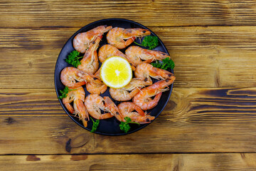 Fototapeta na wymiar Red boiled prawns with lemon and parsley on wooden table. Top view