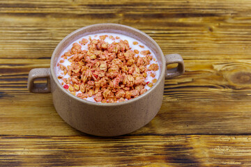 Granola with milk in bowl on wooden table. Healthy breakfast concept