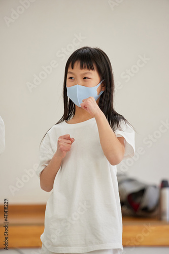 教室でマスクを付けて空手を練習している小学生の女の子の姿 Wall Mural Zheng Qiang