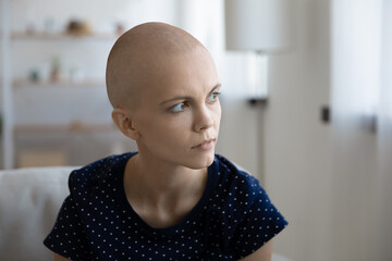 Unhappy thoughtful millennial Caucasian hairless woman struggle with oncology look in distance feel...