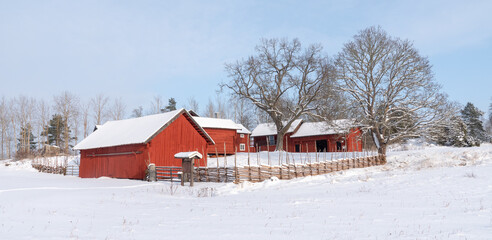 Farm barn and house in a cold winter landscape with snow and frost