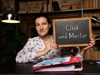 Business concept meaning Click and Mortar with sign on black card in hand.