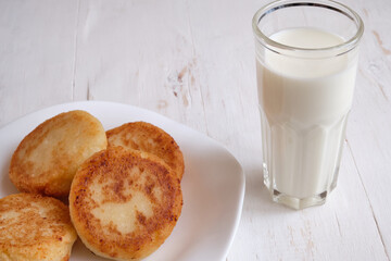 freshly baked cheesecake with milk for breakfast, on a white wooden background