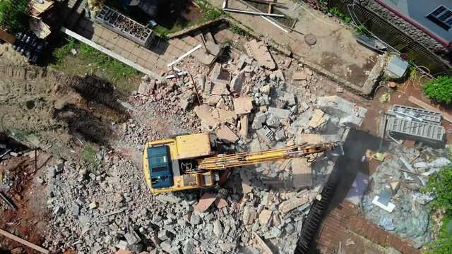 Excavator operates with rubble of abandoned cottage at site
