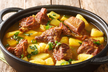 Aloo gosht is a meat curry popular in Pakistani, Bangladeshi and North Indian cuisine closeup in the pan on the table. Horizontal