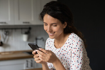 Close up of smiling young Caucasian woman look at smartphone screen texting messaging online. Happy millennial female use cellphone browse wireless internet in device. Online communication concept.