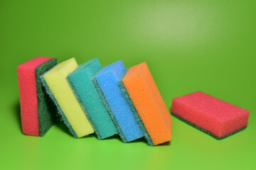 Sponge for washing dishes and plumbing on a green background. Detergents for kitchen for cleaning, toilet and bathroom. Abrasive sponges for wash of dirty on ceramic. Anti-bacterial liquids