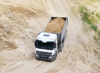 Truck with tipper semi trailer transported sand from the quarry. Dump truck working in open pit mine. Sand and gravel is excavated from ground. Mining industry