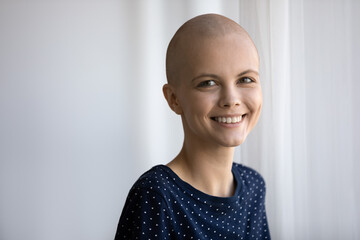 Close up portrait of smiling young hairless Caucasian female cancer patient look at camera feeling...