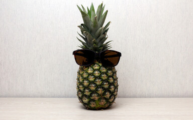 Pineapple in sunglasses. Sunglasses on pineapple on wooden table