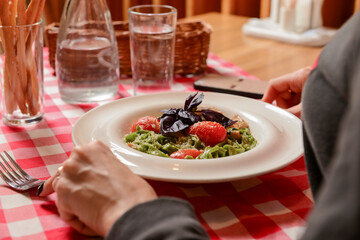 Young attractive woman eating meal set of spaghetti, green spinach pasta. Still life, eating out in restaurant.