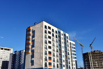 Tower cranes in action on blue sky background. Construction of new multi-storey buildings. Residential building is being constructed use of crane. Pouring of concrete in formwork