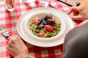 Young attractive woman eating meal set of spaghetti, green spinach pasta. Still life, eating out in restaurant.