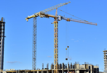 Tower cranes in action on blue sky background. Construction of new multi-storey buildings. Residential building is being constructed use of crane. Pouring of concrete in formwork