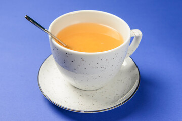 Cup of ginger citrus tea over blue background. Tea time concept.
