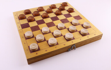 Checkers game. Wooden checkers on a blackboard on a white background