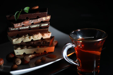 A bar of milk chocolate. Homemade milk chocolate with almonds and dried strawberries. Pieces of milk chocolate. Set of milk chocolate with tea.