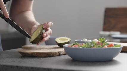 man make salad with kale, mozzarella, avocado and cherry tomatoes, cut avocado