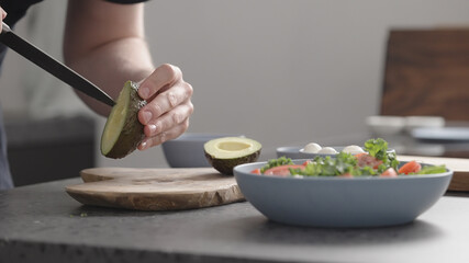 man make salad with kale, mozzarella, avocado and cherry tomatoes, cut avocado