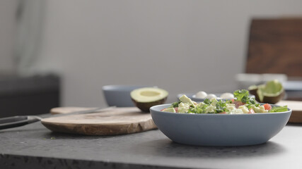 man make salad with kale, mozzarella, avocado and cherry tomatoes, cut avocado
