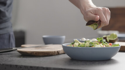 Obraz na płótnie Canvas man make salad with kale, mozzarella, avocado and cherry tomatoes, cut avocado