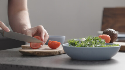Obraz na płótnie Canvas man make salad with kale, mozzarella, avocado and cherry tomatoes, cut cherry tomatoes