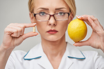 nutritionist doctor healthy lifestyle concept - holding fresh organic lemon fruit and vitamin...