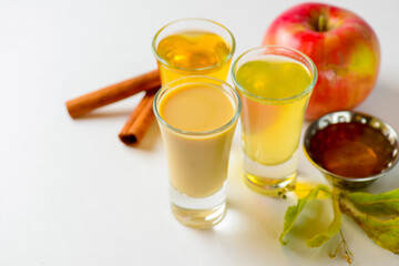 Fresh organic apple cider with apples and cinnamon over white background. Close up three glasses.