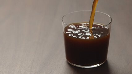 pour coffee in tumbler glass on walnut wood table with copy space