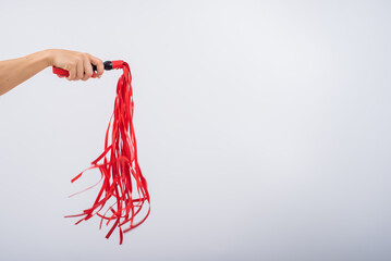 Red leather whip in female hands on a white background. Copy space.
