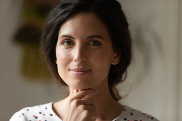 Close up portrait of happy young Caucasian brunette woman look at camera posing thinking or...