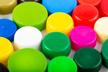 Many multi-colored plastic bottle caps on a white background.