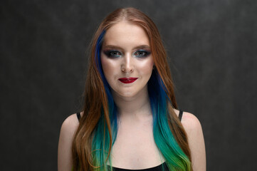 Portrait with makeup girl with dyed hair. Caucasian model on gray background