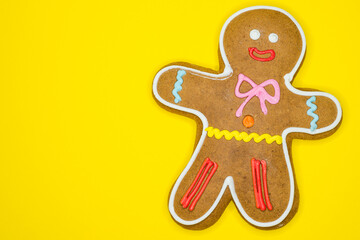 Gingerbread man decorated with colored icing isolated on yellow background with text space