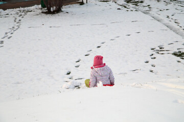 A child on a sled goes down a snow slide.