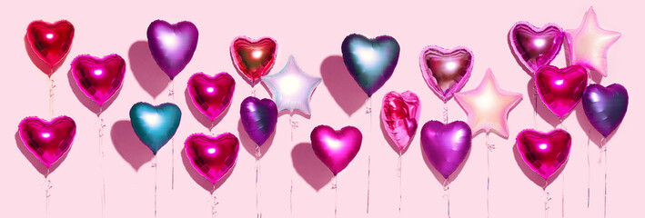 Air Balloons. Bunch of colorful purple, pink, blue heart shaped foil balloons on pink background. Love. Holiday celebration. Valentine's Day party decoration. Birthday. Metallic balloon. Wide screen.