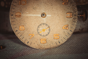 Vintage grunge background of an old clock. Abstract texture covered with dust, dirt, scratches. Macro photography in light tinted